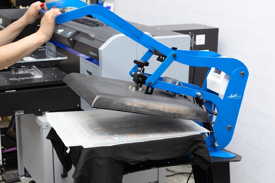 The powdered adhesive can be cured by hovering a heat press above the transfer film.